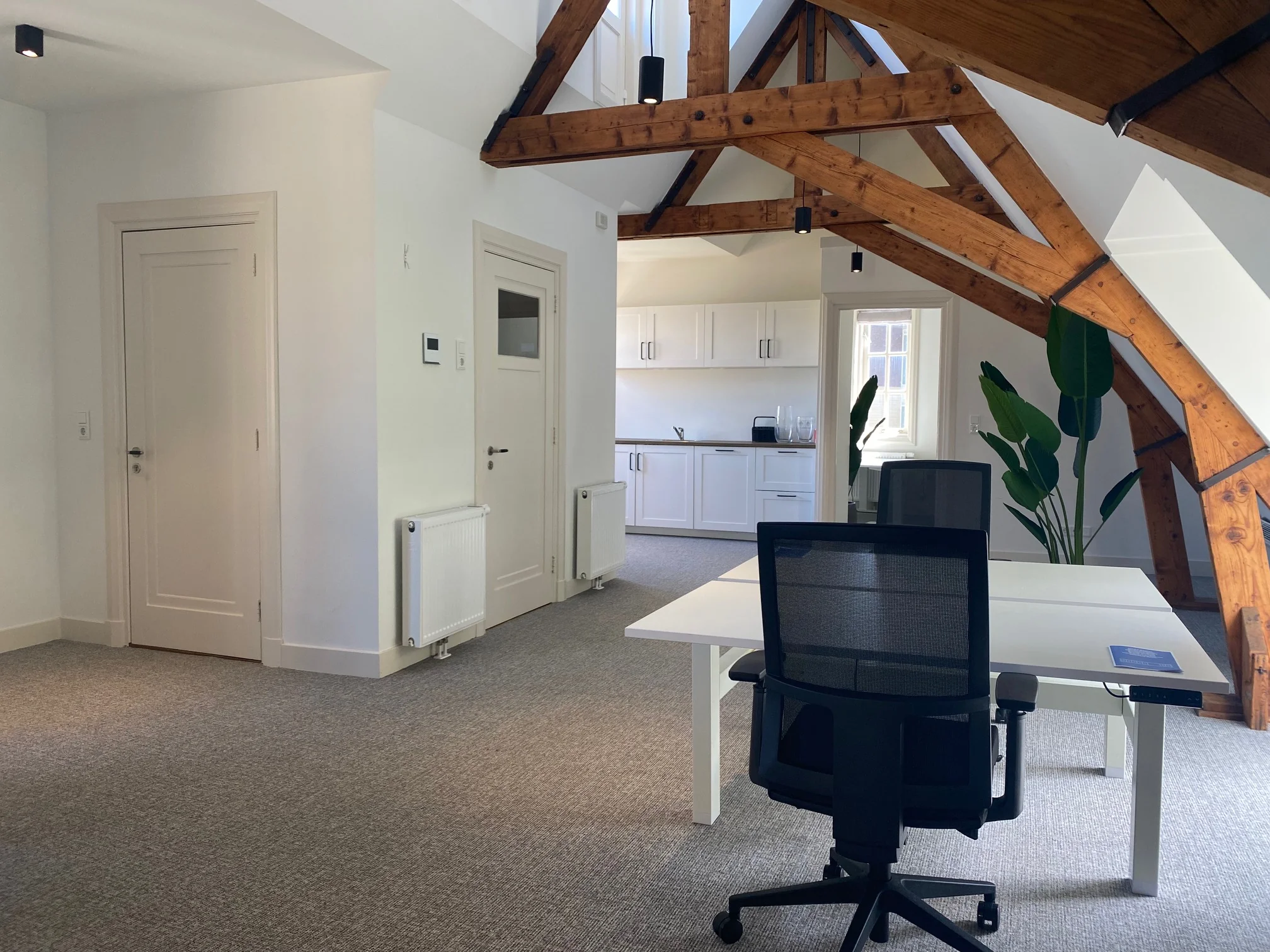 Modern kantoorinterieur aan de Kleine Houtweg met zichtbare houten dakconstructie en open kitchenette.